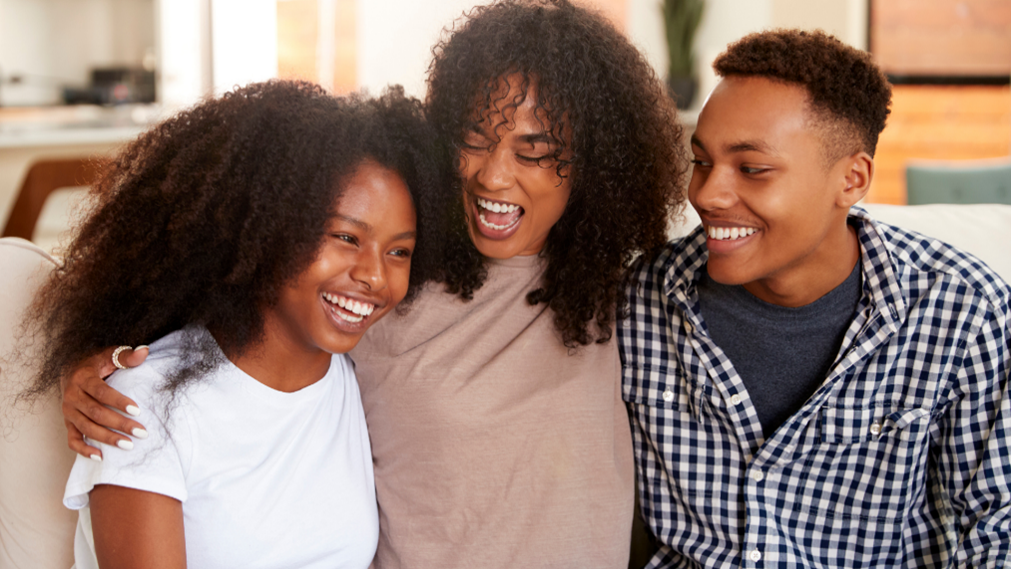 Two African American youth and an adult African American woman smiling.  