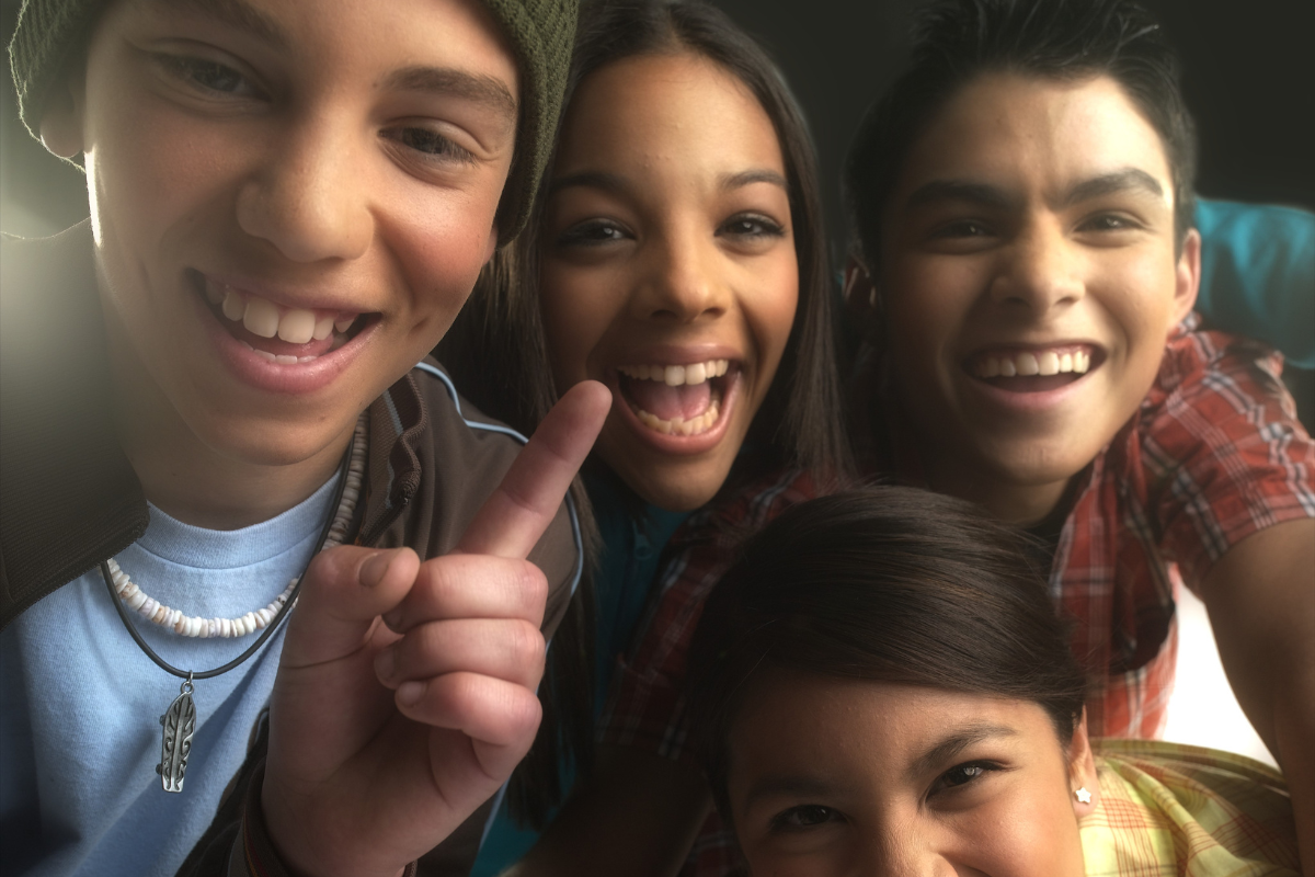 Four diverse teens smiling.