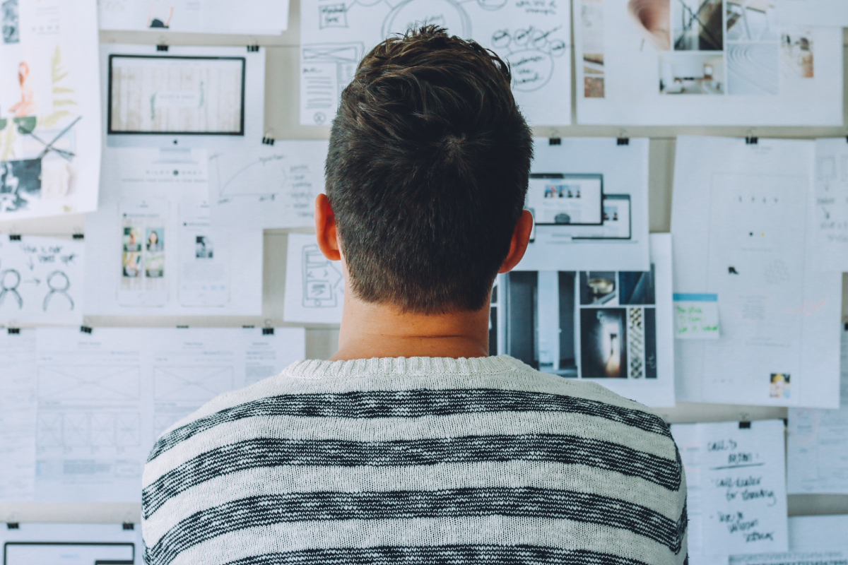 Back view of a person looking at a wall of pictures and notes