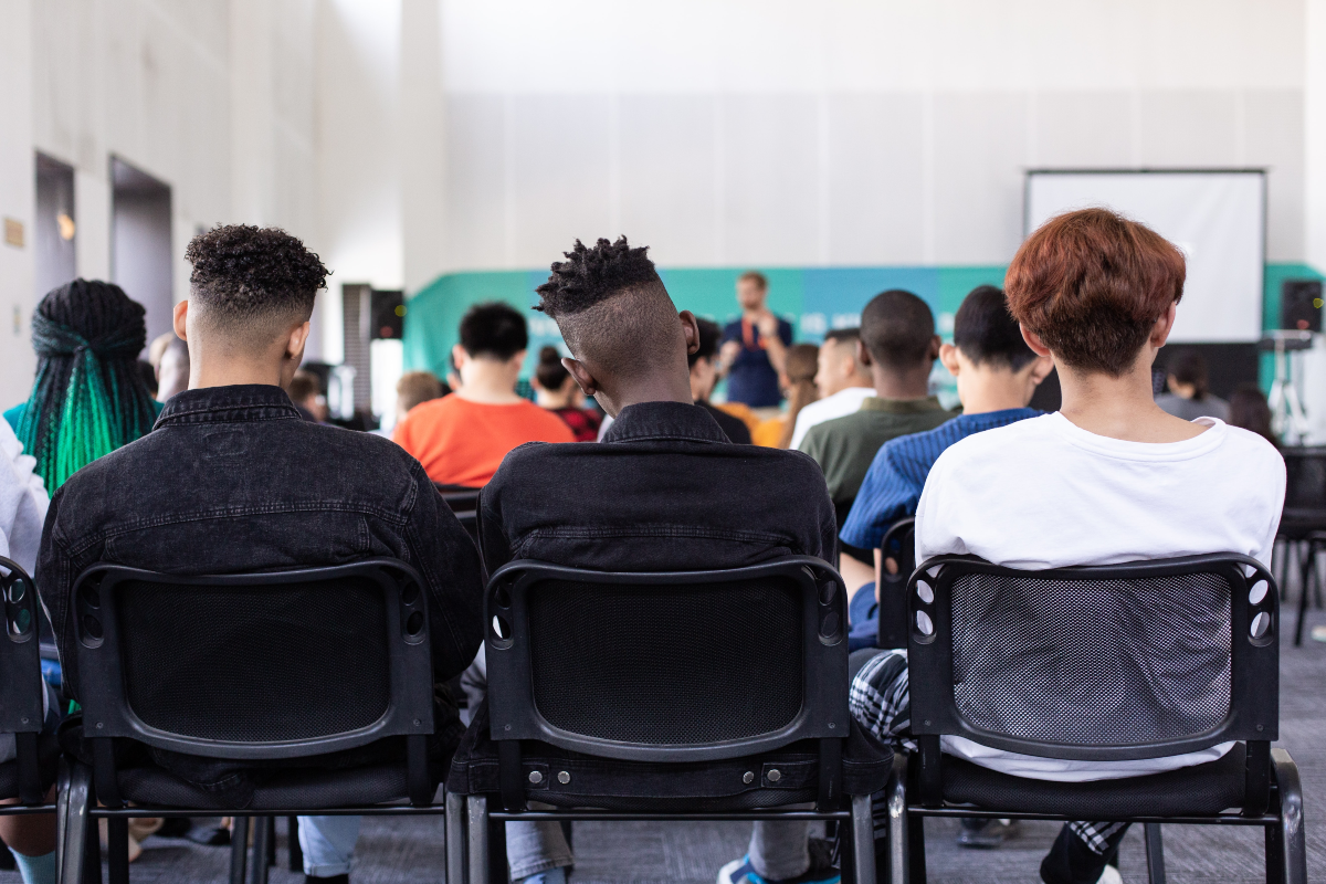 Image that shows a group of teenage boys from behind sitting in a classroom