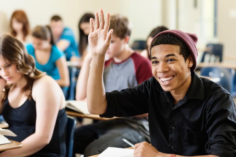 Male teen raising hand in class