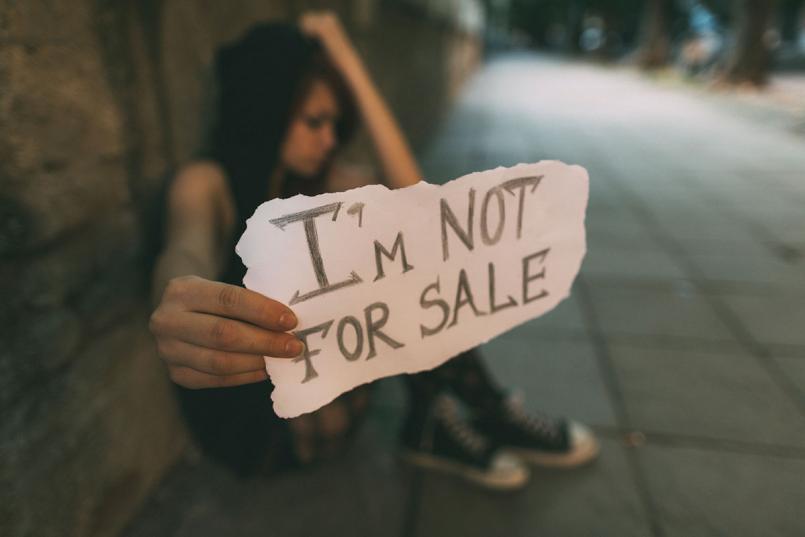 Girl in street holding an "I'm not for sale" sign