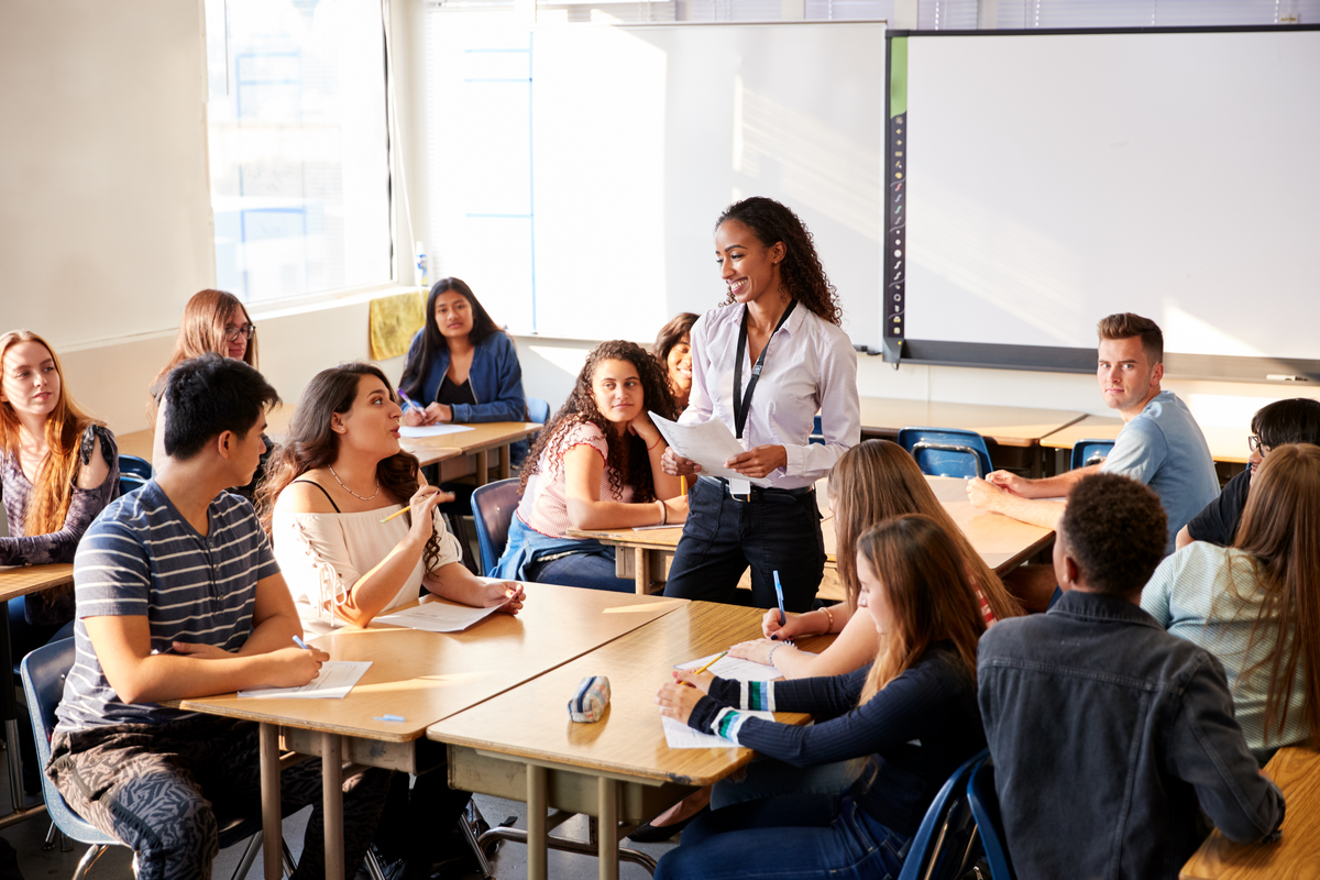 Female highschool teacher talking to students in classroom 