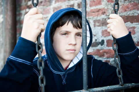 Youth with their hands on chains, looking away from the camera