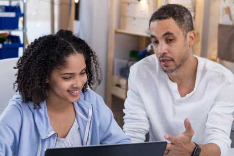 Adult and youth sitting in front of a computer. 