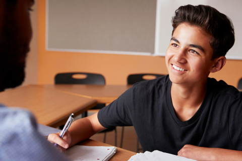 Adult talking to male student.