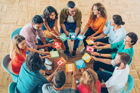 Group of people sitting together holding different pictures of media icons.