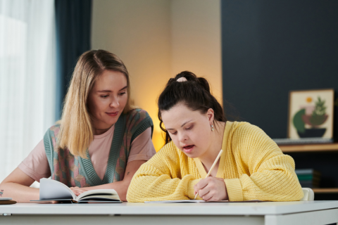 A teacher working with a youth with a disability.