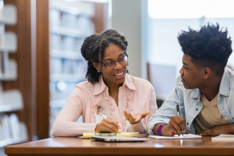 Adult talking to male adolescent.