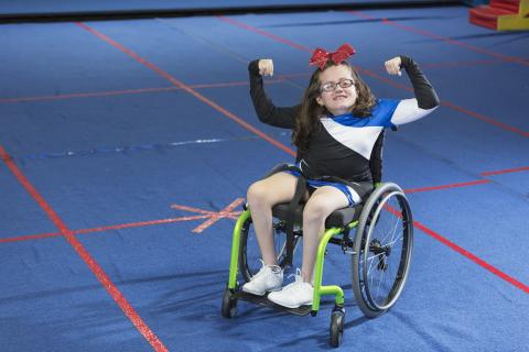 Youth in a wheelchair with their arms up in a strong pose. 