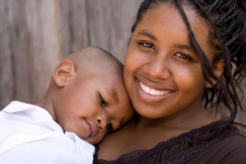 Smiling teen mother holding child 