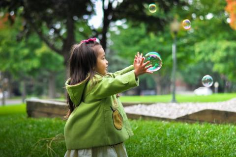 Little girl playing with bubbles outside.
