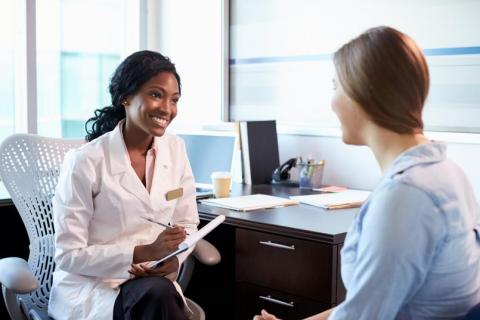 Female healthcare professional in office talking to teen girl.