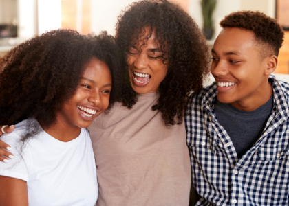 Two African American youth and an adult African American woman smiling.  