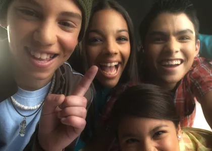 Four diverse teens smiling.