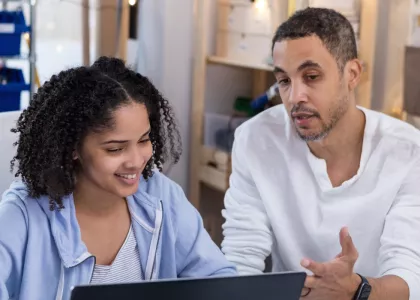 Adult and youth sitting in front of a computer.