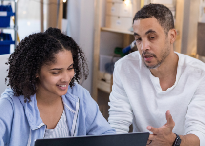 Adult and youth sitting in front of a computer. 