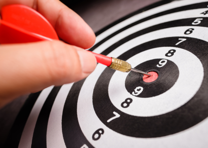 Dartboard, with a hand pulling a dart out of a bullseye