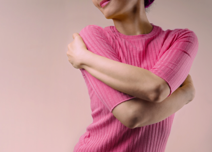 Person in pink clothes hugging themself.