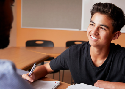 Adult talking to male student.