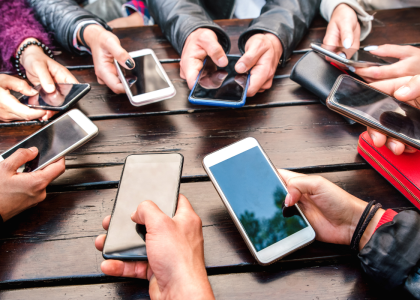 A group of people in a circle are holding their phones towards the center of the group.