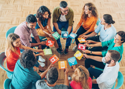 Group of people sitting together holding different pictures of media icons.