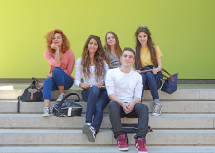 A group of young adults sitting and looking towards the viewer.