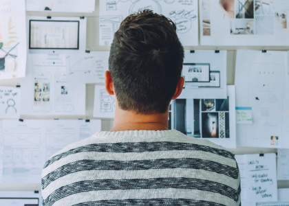 Back view of a person looking at a wall of pictures and notes