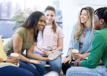 Group of 5 diverse teens sitting in a circle and talking.