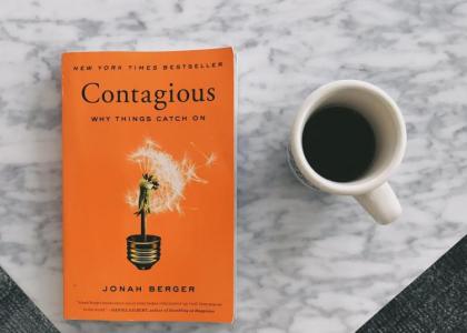 The book Contagious sits on a counter next to a mug of coffee.