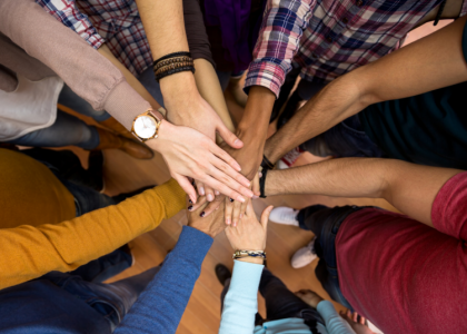 Group of individuals putting their hands together in a circle 