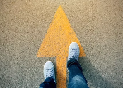 Person standing on yellow arrow on the ground. The arrow points forward.