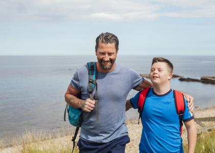 Adult with arm around youth in front of a body of water. 