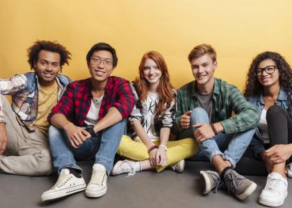 Group of five teens - two young women and three young men - facing the camera and smiling.