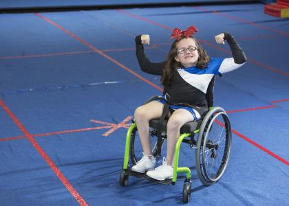 Youth in a wheelchair with their arms up in a strong pose. 
