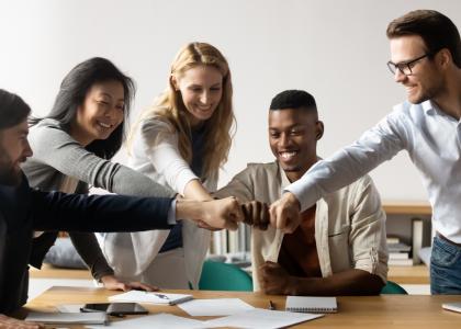 Diverse group of young professionals giving a team fist-bump as they collaborate.