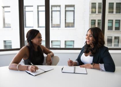 Two women sitting at a table talking.