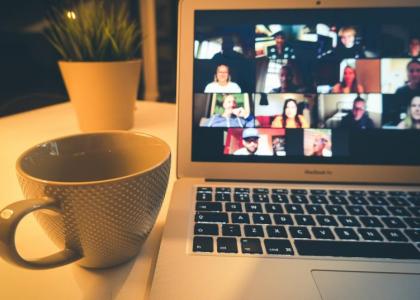 Image of a coffee cup next to a computer showing a virtual meeting 