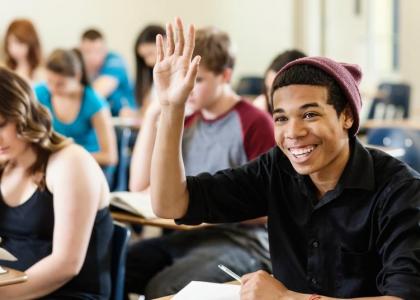 Male teen raising hand in class