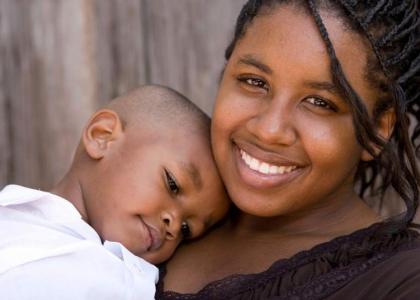 Smiling teen mother holding child