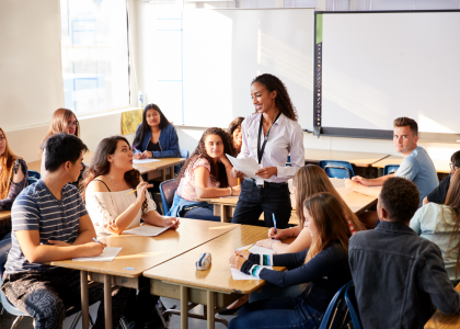 Female highschool teacher talking to students in classroom 