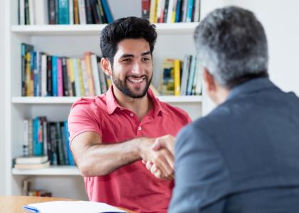 Two businessmen in an office are shaking hands.