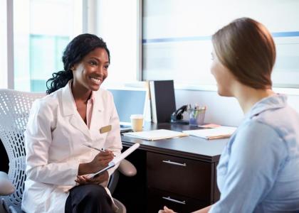 Female healthcare professional in office talking to teen girl.